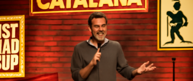 Un paisatge natural amb muntanyes verdes, un riu que flueix tranquil·lament i un cel blau clar amb núvols esponjosos.